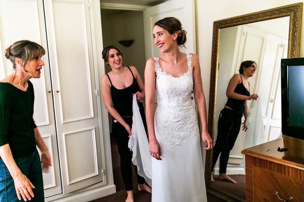 Novia riendose con la madre mientras la hermana le sostiene el vestido e mlos preparativos de un casamiento en Buenos Aires