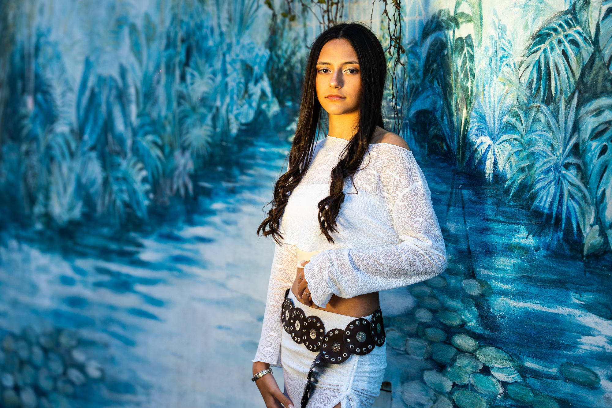 Quinceañera frente a un mural azul de vegetación