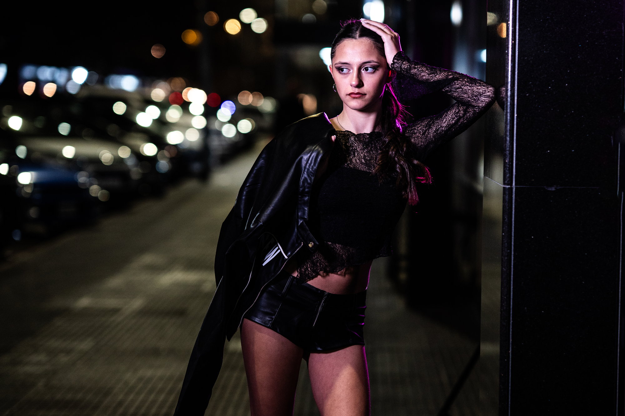 Quinceañera de noche en la vereda, con las luces de los autos